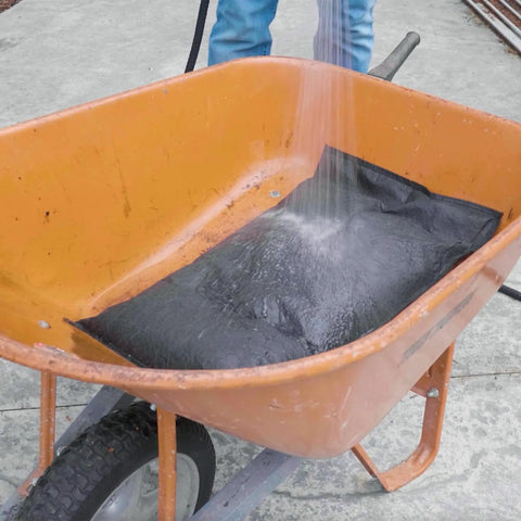 Water Activated Flood Bags Two Pack No Sand No Labor Needed Ready To Use; bag expanding with water in a wheelbarrow.