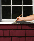 Hand applying triple thick high build binding primer on window, sealing weathered surfaces for smooth indoor or outdoor makeover.