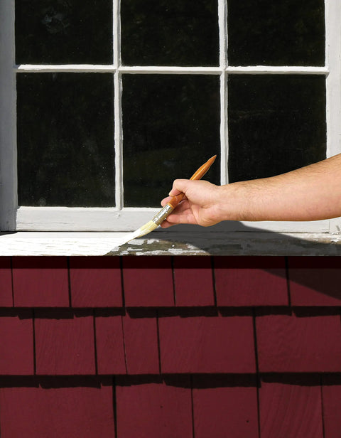 Hand applying triple thick high build binding primer on window, sealing weathered surfaces for smooth indoor or outdoor makeover.