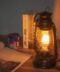 Pack Of 2 Vintage Rustic Lantern Lamps With Edison LED Bulbs, Bronze Rust Finish, on a nightstand beside a book and canister