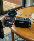 Person using smartphone to control Beam Mini Portable Guitar Amp With NAM Compatibility, 17 Models, 35 Plus Effects, USB C And Bluetooth.