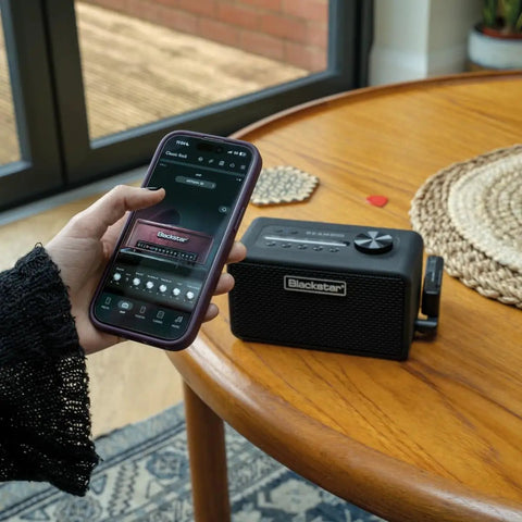 Person using smartphone to control Beam Mini Portable Guitar Amp With NAM Compatibility, 17 Models, 35 Plus Effects, USB C And Bluetooth.