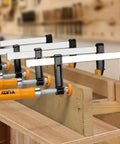 Four Pack 6-Inch Bar Clamps For Woodworking Heavy-Duty Steel F-Clamps With 300 Lb Load And Ergonomic Handles Ideal For Glue-Ups DIY Projects Home Renovations Garage Or Workshop Woodworking clamping wood boards in a workshop