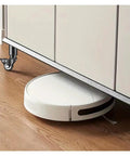 Kick Heavy Moves To The Curb 4 Pack Swivel Caster Wheels under furniture with white robotic vacuum on hardwood floor.