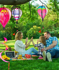 Family picnic under Four Pack Colorful Hot Air Balloon Wind Spinners For Yard Decor With Curly Tails That Spin In The Wind