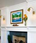 Modern Plug In Gold Wall Sconce Set Of 2 With Adjustable 180 Degree Light Heads For Bedroom And Living Room Easy Install Sleek Contemporary Look And Warm Luxe Glow. Installed around a framed painting on a white mantelpiece.