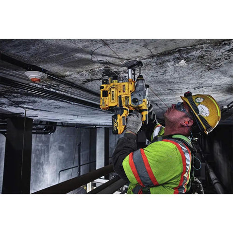 Worker using Onboard Dust Extractor for 1-1/8-Inch SDS Plus Rotary Hammers in a tight space on a ceiling.