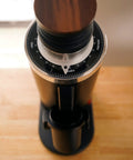 Heavy Duty 64Mm Flat Burr Electric Coffee Grinder Designed For Single Dosing Habits With Anti Popcorn Guard And Zero Static Hiccups Grinding Every Batch Bang On For Your Morning Rush In Glossy Black, overhead view with wood lid.