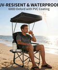 Man sitting on Heavy Duty Folding Camp Chair With Adjustable Canopy And Side Table, Oversized Directors Chair on the beach