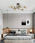 Lit Modern Glass Globe Sputnik Chandelier Flush Mount Ceiling Light in Black and Gold Finish for Dining Room Kitchen and Hallway Farmhouse Style Decor, installed in a bedroom setting, showcasing its six smoky glass globes.