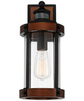 Rock Solid Black Motion Sensor Outdoor Wall Sconce With Zero Fuss Industrial Craftsmanship And Reliable Nighttime Security Lighting For Front Porch Or Driveway, showcasing a metal body with glass shade.