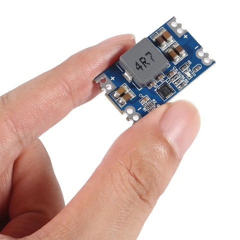 Person holding a compact Five Volt Five Amp Mini560 Buck Converter Module For DIY Projects, showing blue circuit board and components.