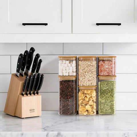 Six Pack Airtight Glass Storage Canisters With Square Lids Set For Flour Cereal Sugar Tea Coffee Beans Snacks Pantry Organization Kitchen Jars 0.7 Qt 1.2 Qt 1.6 Qt filled with food items on a kitchen counter alongside a knife block.