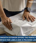 Hands sealing a white poly mailer 10x13 pro-grade durable waterproof tear-proof shipping envelope on table, 100 pack visible