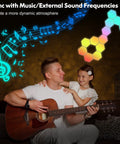 Father playing guitar with daughter, colorful hexagon LED wall panels syncing to music, RGB hex tiles in warm room lighting