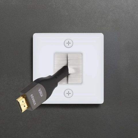 Front view of white hole-saw wall plate with brushed metal brush insert; HDMI cable partially inserted