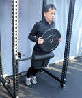 Person using Single Leg Squat Roller Attachment for Power Rack and Home Gym with weight plate, enhances quads glutes hamstrings.