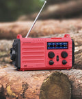 Red NOAA Weather Radio With Battery Backup And Solar Hand Crank, Portable AM FM Shortwave Receiver on logs outdoors