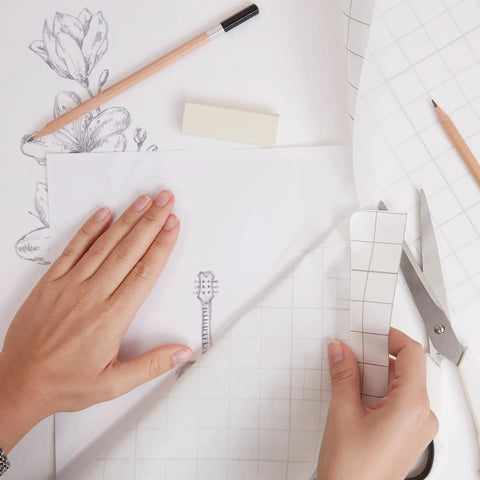 Frisket Masking Film Matte 10 Inch By 4 Yard for artists used over pencil drawing with grid lines, showing hands applying film