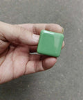Hand holding glossy ceramic square cabinet knob, 1.25 inch green, six pack, kid friendly, with three size screws easy install