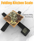 Folding Kitchen Scale 5000g/1g, Space Saving X Fold Design, LCD Display, Tare Function. Black scale with nuts on top.