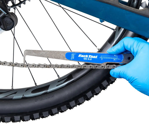 Hand using No Guesswork Bicycle Chain Wear Checker Pro Grade Gauge For Half Inch Pitch Chains on bike chain