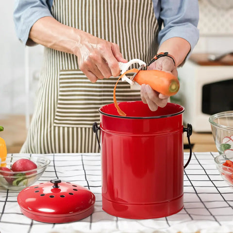Person using red metal pail for countertop waste recycling from Outdoor Dual Chamber 43 Gallon Compost Tumbler Kit With 1.5 Gallon Kitchen Bin Lid And Charcoal Filter Rotating Design For Easy Separation Black And Red Metal Pail For Countertop And Outdoor Waste Recycling.