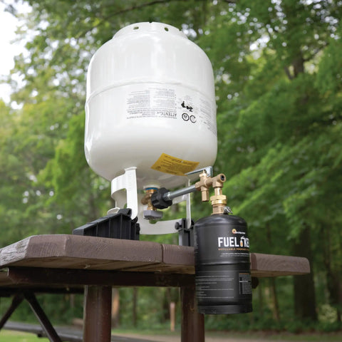 One Pound Propane Refill Kit For Refillable Tank shown with stabilizing feet on wooden table in outdoor setting