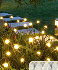 Solar Powered Firefly Lights 8 LED Outdoor Garden Lights Waterproof With Swaying Starburst Motion And Warm White Glow 4 Pack illuminating a pathway at night