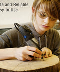 Rotary burr tool being used by a person wearing safety glasses to carve a wooden log (front view).
