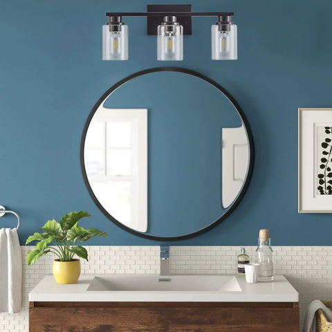 Sleek Matte Black 3 Light Vanity Light With Clear Glass Shades For Bathroom over round mirror in modern bathroom.