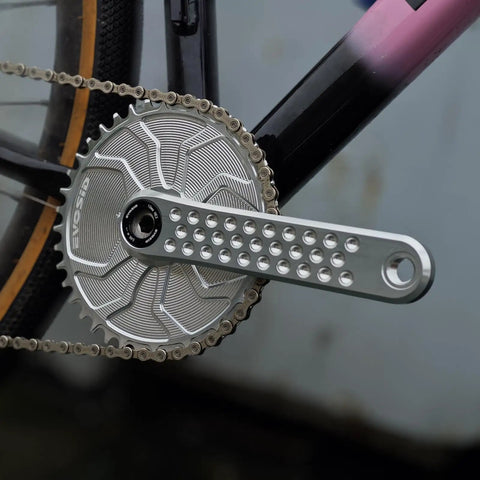 Close-up of road bike crank set with 3 bolt direct mount, 160mm crank arm, silver finish, installed on bike.