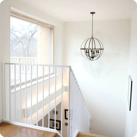 Harmon 27 Inch Six Light Dope Modern Farmhouse Armillary Chandelier With Sphere Globe Design In Smoked Birch Finish hanging above staircase