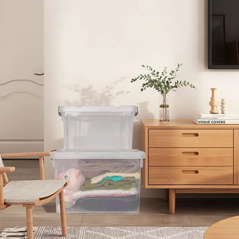 Big Boss 90 Quart Clear Plastic Storage Bins 8 Pack With Snap On Lids stacked with clothes in a cozy living room setting.