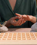 Dope Stackable Jewelry Organizer Tray Featuring Thirty Six Durable Wooden Grids For Sorting Beads Bracelets Pendants And Earrings on display with hands holding jewelry.