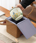 Top Shelf Ceramic Tea Tin With Woven Rattan Travel Case, Stunning Mountain Landscape Design, Go To Stash Jar For Loose Leaf Tea Or Specialty Coffee Beans In Slate Blue being placed into a rattan pouch.
