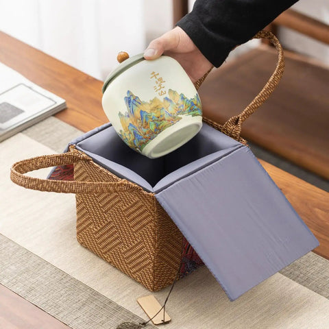 Top Shelf Ceramic Tea Tin With Woven Rattan Travel Case, Stunning Mountain Landscape Design, Go To Stash Jar For Loose Leaf Tea Or Specialty Coffee Beans In Slate Blue being placed into a rattan pouch.