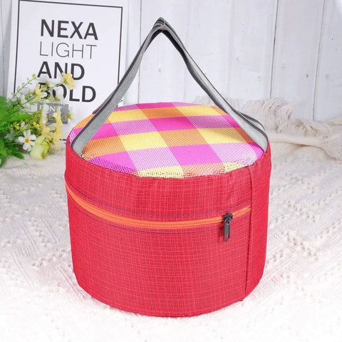Red plaid insulated cooler bag with handle, round shape, zipper closure, ideal for picnics on white blanket.