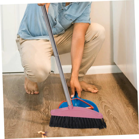 A person using a Heavy Duty Pink Broom With Extended Handle Sweeps Indoors And Outdoors, cleaning hardwood floor.