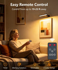 Woman using remote control for Killer Glow Two Pack Battery Operated Picture Lights With Remote in cozy living room.