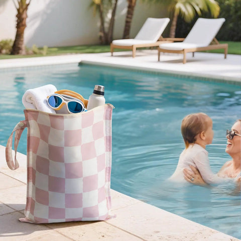 Checkered pink waterproof wet dry bag by pool, holding towel and sunglasses. Waterproof Wet Dry Bags Set Of 2 For Swimwear And Baby Clothes Leakproof Reusable Pouches With Durable Zipper Travel Laundry Daycare Must Have Stays Dry And Odor Free Holds Wet Swimsuits Diapers And Gym Gear