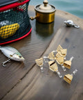 Stainless steel fishing bite alarms set with clips on a table beside fishing lures and tackle box for freshwater and saltwater fishing.