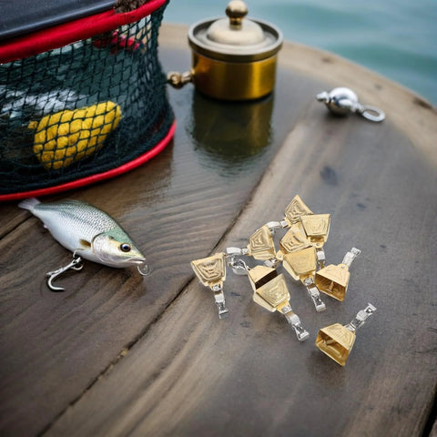 Stainless steel fishing bite alarms set with clips on a table beside fishing lures and tackle box for freshwater and saltwater fishing.