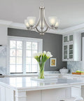 Farmhouse 24 Inch Five Light Chandelier With Clear Glass Shades in modern kitchen with white cabinetry.
