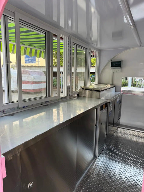 Interior view of a custom mobile coffee and pastry trailer featuring stainless steel counters, fridge, and sink for quick street vending.