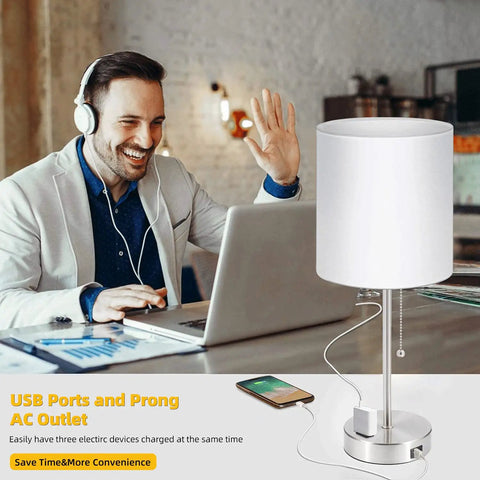Man using laptop beside 2 Pack Bedside Table Lamps With USB Port And AC Outlet, Pull Chain, White Shade On Nickel Base