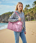 Woman with 45L Waterproof Duffle Bag For Women Lightweight Carry On Weekender With Separate Shoe Pocket And Multiple Internal Pockets Durable Travel Tote For Gym And Weekend Getaways Pink on a beach