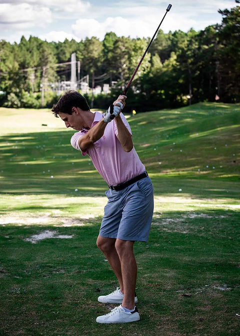 Golfer practicing swing on green with Golf Swing Speed Trainer System To Get Longer Drives Through Overspeed Training With CNC Milled Weighted Sticks.