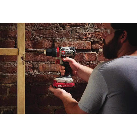Person using 20V Max Cordless Drill Driver Kit with Two Batteries and Charger, One Half Inch Chuck on a wooden frame against a brick wall.