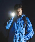 Person using 12 Pack Mini LED Pen Flashlights With Clip, compact flashlight illuminating path at night, wearing blue jacket.